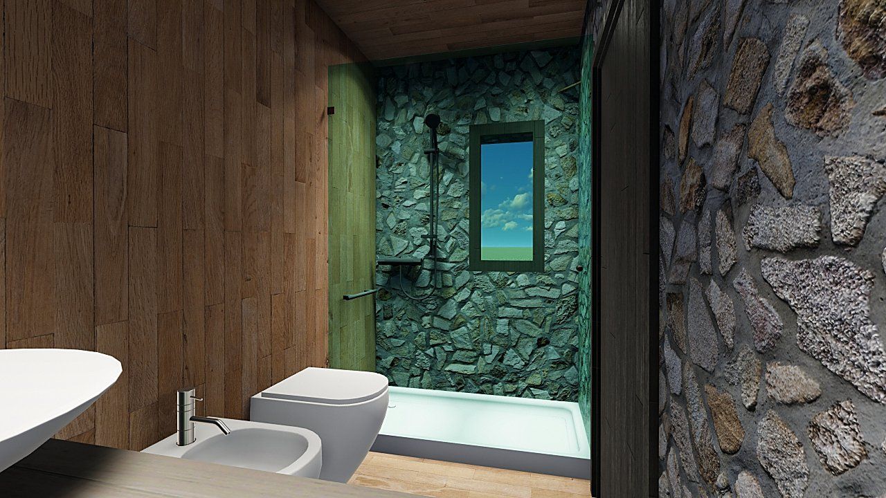 Il bagno con la parete in pietra e la doccia verso la finestra