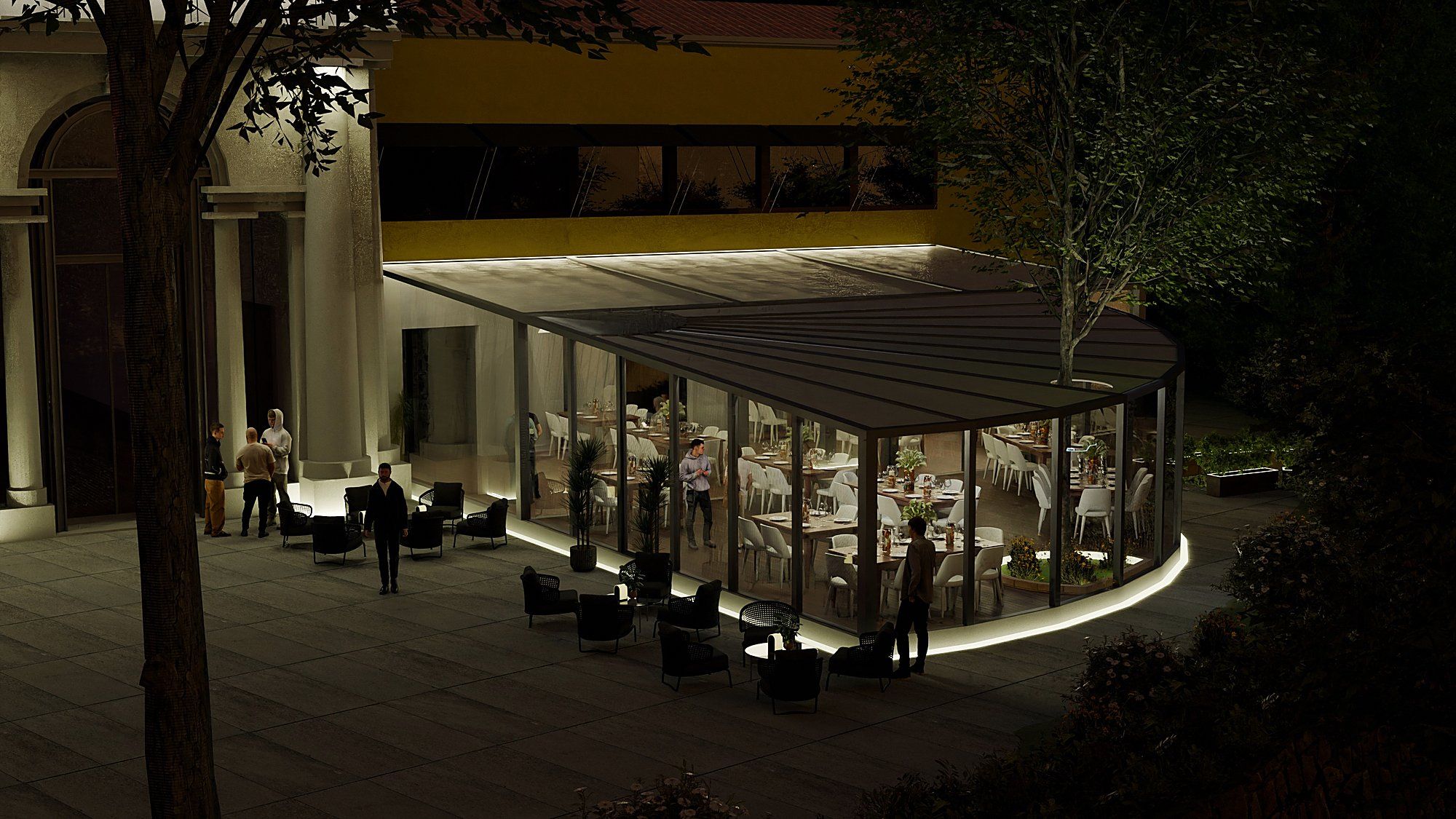 La veranda di vetro accanto alla loggia, di notte: la curva illuminata alla base, l’albero che la attraversa e i tavoli apparecchiati